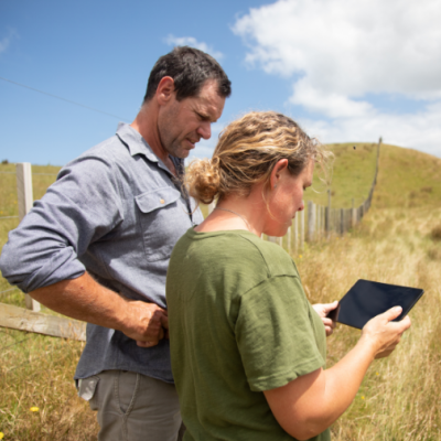 Two farmers in a field looking at information on a tablet device