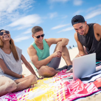 Three young friends looking at their laptop on the beach 