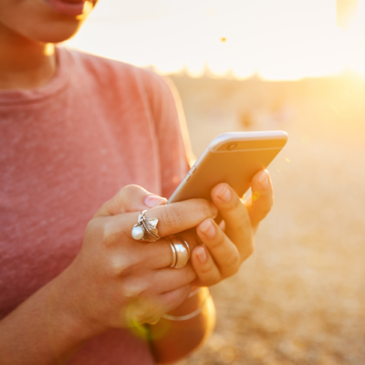 Women texting on her phone on a beach at sunset