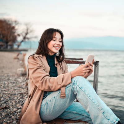 Women sitting on the edge of a pier looking at her mobile phone